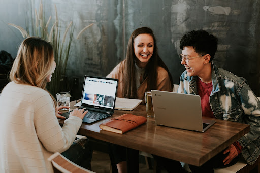 Chosing a domain name to match your brand | People around table working on laptops Photo